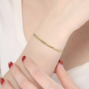 Detail showing the golden snake chain bracelet with star-shaped patterns on the metal links