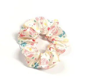 Detail of satin scrunchie with ladybug and floral print on cream background
