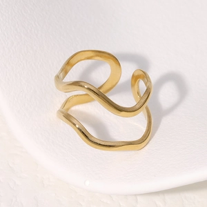 Macro shot of double-layered wavy gold ring with polished finish on textured background