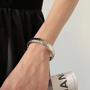 Détail d'un bracelet manchette matelassé argenté avec texture métallique polie