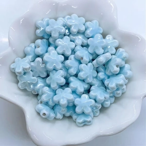 Dettaglio di perline in ceramica a fiori azzurri in un contenitore bianco per gioielli