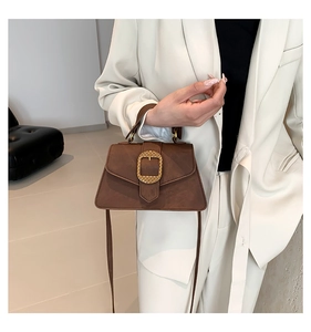Brown matte suede handbag with gold buckle shown on a cream suit outfit for women