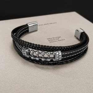 Detail of multi-layer black braided leather bracelet with silver textured magnetic clasp