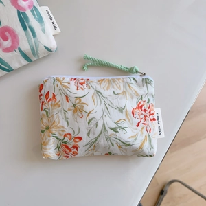 Detailed macro view of small floral cotton bag with zipper and green cord puller