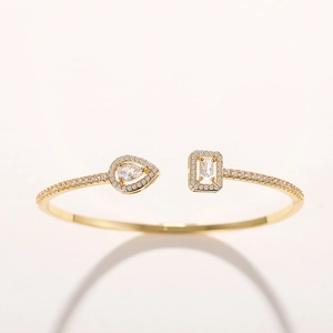 Macro detail of gold open bangle featuring pear and rectangular cubic zirconia stones