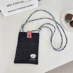 Detail of denim crossbody phone bag with dog embroidery and colorful beaded strap