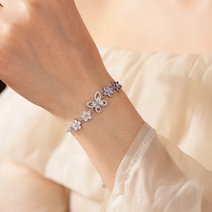 Detailsicht eines silbernen Blumen und Schmetterling Armbands mit lila Zirkon am Handgelenk