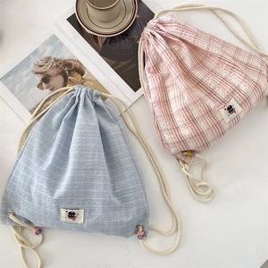 Close-up of pastel plaid drawstring backpacks with colorful beaded rope details
