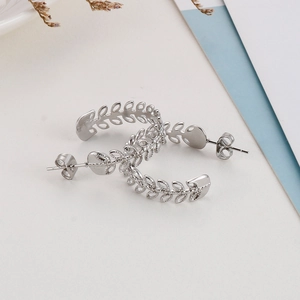 Nahaufnahme silberner C-förmiger Blattohrringe mit detaillierter Olivenzweig-Textur