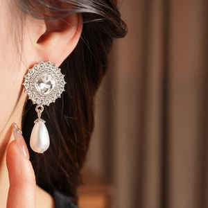 Close-up of vintage silver earrings with rhinestones and white pearls on model