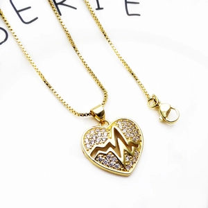 Close-up of gold-plated heart pendant with heartbeat design and micro-set cubic zirconia