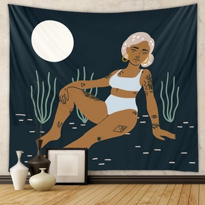 Close-up of bohemian wall tapestry featuring tattooed woman under full moon in a desert