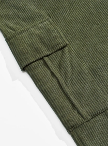 Detailed macro view of green corduroy fabric and cargo pocket flap with ribbed texture