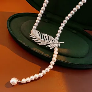 Elegant pearl necklace featuring a sparkling zircon-encrusted feather pendant on velvet