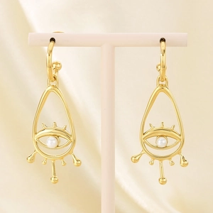 Detailed view of hollow evil eye drop earrings with pearls on a silk background