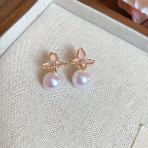 Detail of pink flower stud earring with a lustrous white pearl on fabric background