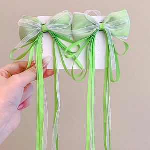 Detail of light organza bow hair clips in green and white with long flowing ribbons