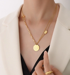 Detail of double-layer gold coin necklace featuring engraved BELOVED pendant on model