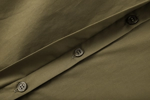 Close-up of olive green cotton poplin shirt featuring detailed brown button fastening