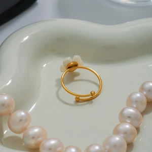 Detail of adjustable gold ring with white flower charm on ivory ceramic tray