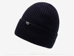 Detail of dark blue knitted beanie showing thick ribbed texture and FEKS metal logo tag