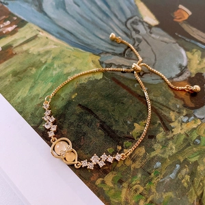 Macro view of adjustable gold-tone bracelet with white zircon and yellow gourd charm