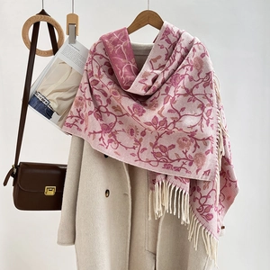 Ethno floral jacquard scarf in pink and white with decorative tassels on beige coat