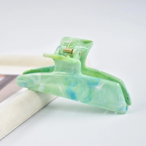 Detail shot of marble green and blue acetate hair claw clip with glossy texture