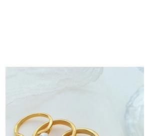 Close-up of gold-plated rings set featuring a heart-shaped opal inlay and pearl detail