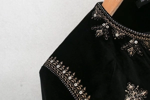 Détails de broderies dorées et paillettes sur col et épaule en velours de soie noir