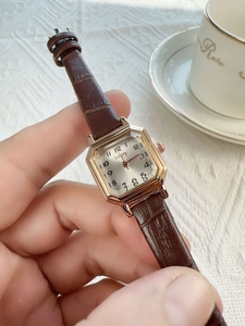 Close-up of retro square gold watch with brown leather strap and Arabic numerals