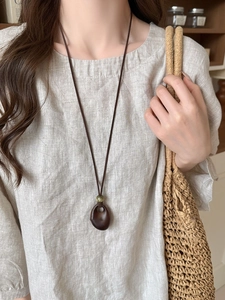 Close-up of vintage resin necklace pendant with green bead on soft linen fabric background