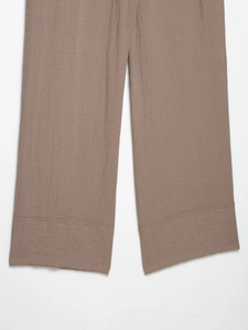 Dettaglio dei pantaloni larghi in cotone e lino beige scuro che mostra la trama del tessuto