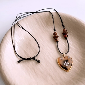 Close-up of heart-shaped tortoiseshell pendant with golden frame and floral details