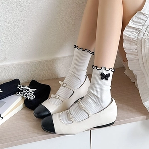 Detailed view of white Lolita socks with black frilly edges and ribbon bows