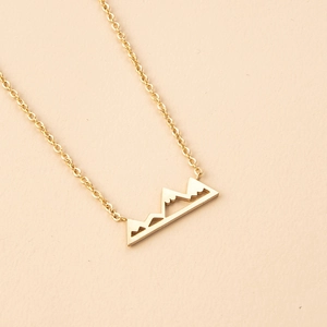 Detail of minimalist mountain peak pendant necklace in gold finish with hollow lines