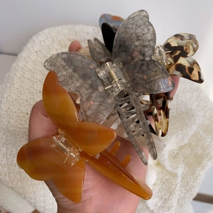 Detailed close-up of three handmade butterfly acetate hair claws in tortoise and stone patterns