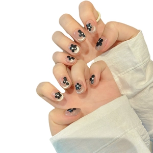 Handcrafted cat-eye press-on nails with black floral designs and sparkling rhinestones