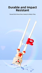 Detail of durable white training chopsticks with red finger rings and cartoon pig topper