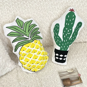 Detail shot of pineapple and cactus shaped decorative cushions on white plush fabric