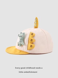 Detail of baby baseball cap featuring a 3D green cartoon dinosaur and soft yellow brim