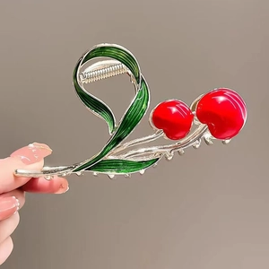 Detailed view of red cherry hair claw clip with green leaves on gold metal base
