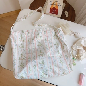 Close-up of floral cotton tote bag with pink stripes on white desk with accessories