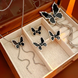Detail view of a black butterfly jewelry set with necklace and earrings in a wooden box