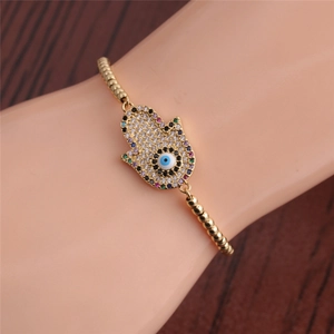 Détail du bracelet Hamsa doré avec zircons colorés et pendentif œil bleu maléfique