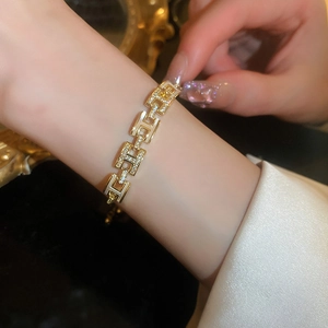 Gros plan d'un bracelet doré à maillons H avec zircons porté au poignet