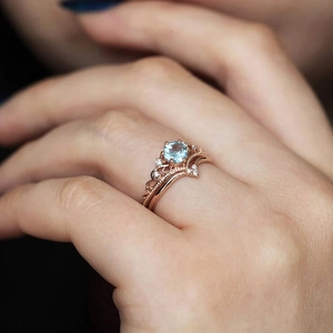 Detailed view of rose gold crown ring set with round blue zircon on a hand