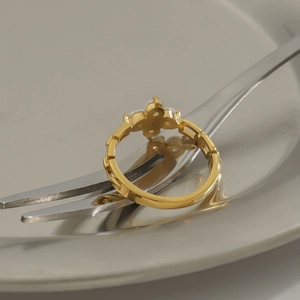 Macro shot of gold clover ring with zircons resting on a metallic fork detail
