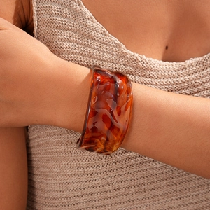 Close-up of wide amber acrylic bangle with marble texture worn by a model