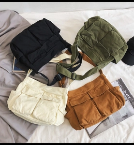 Flat lay view of canvas messenger bags in black, army green, beige, and khaki colors